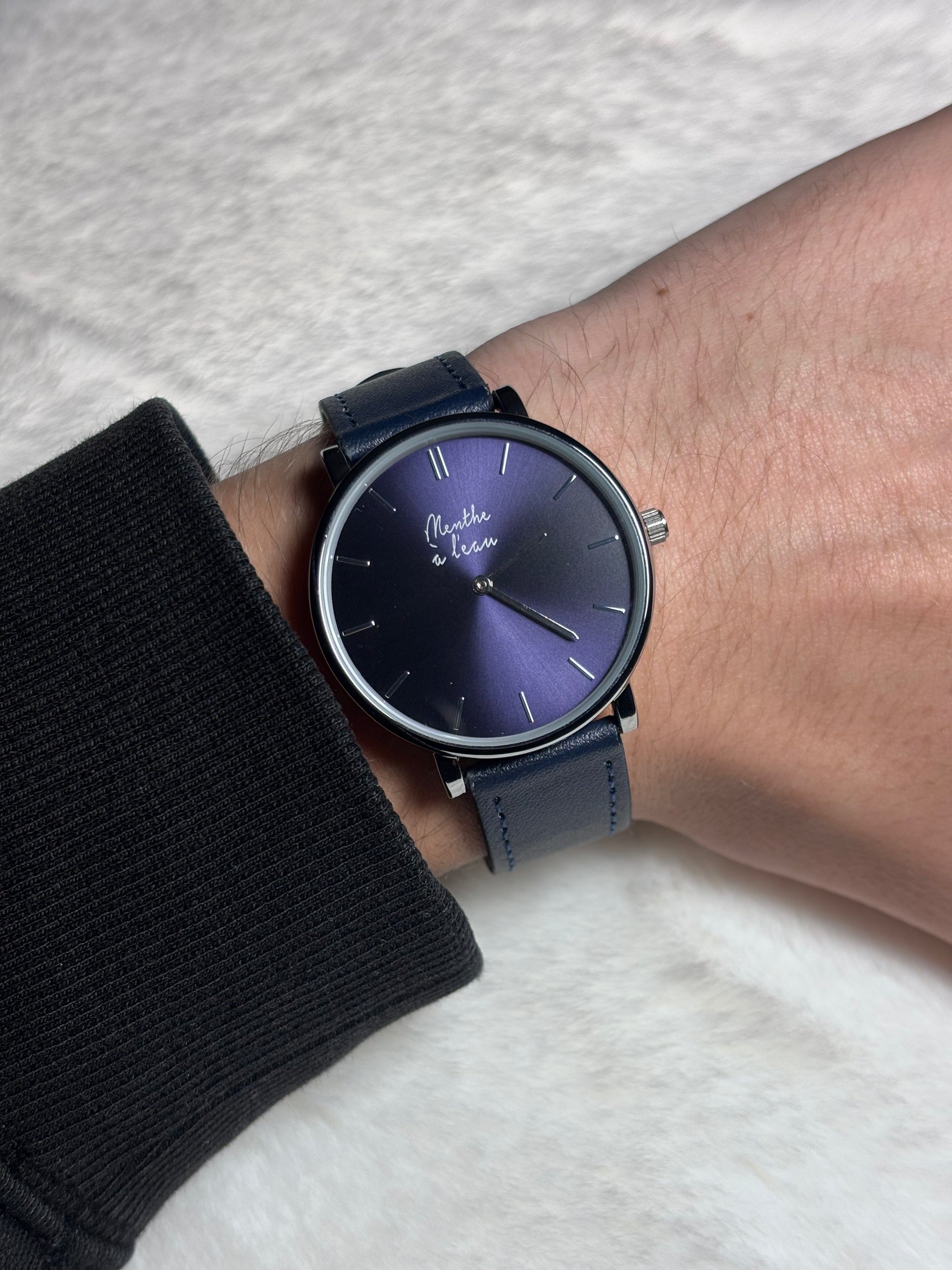 Montre L’Indécise portée au poignet, avec cadran bleu et bracelet en cuir bleu foncé